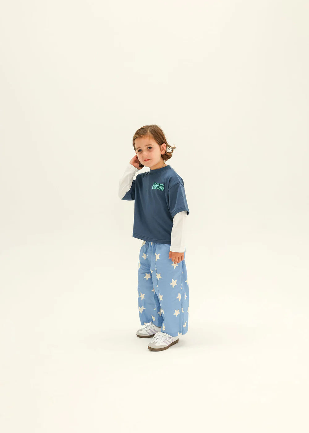 Child wearing a blue shirt and light blue pants with star pattern on a white background