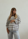 Woman wearing a striped sweater and light blue jeans against a plain background