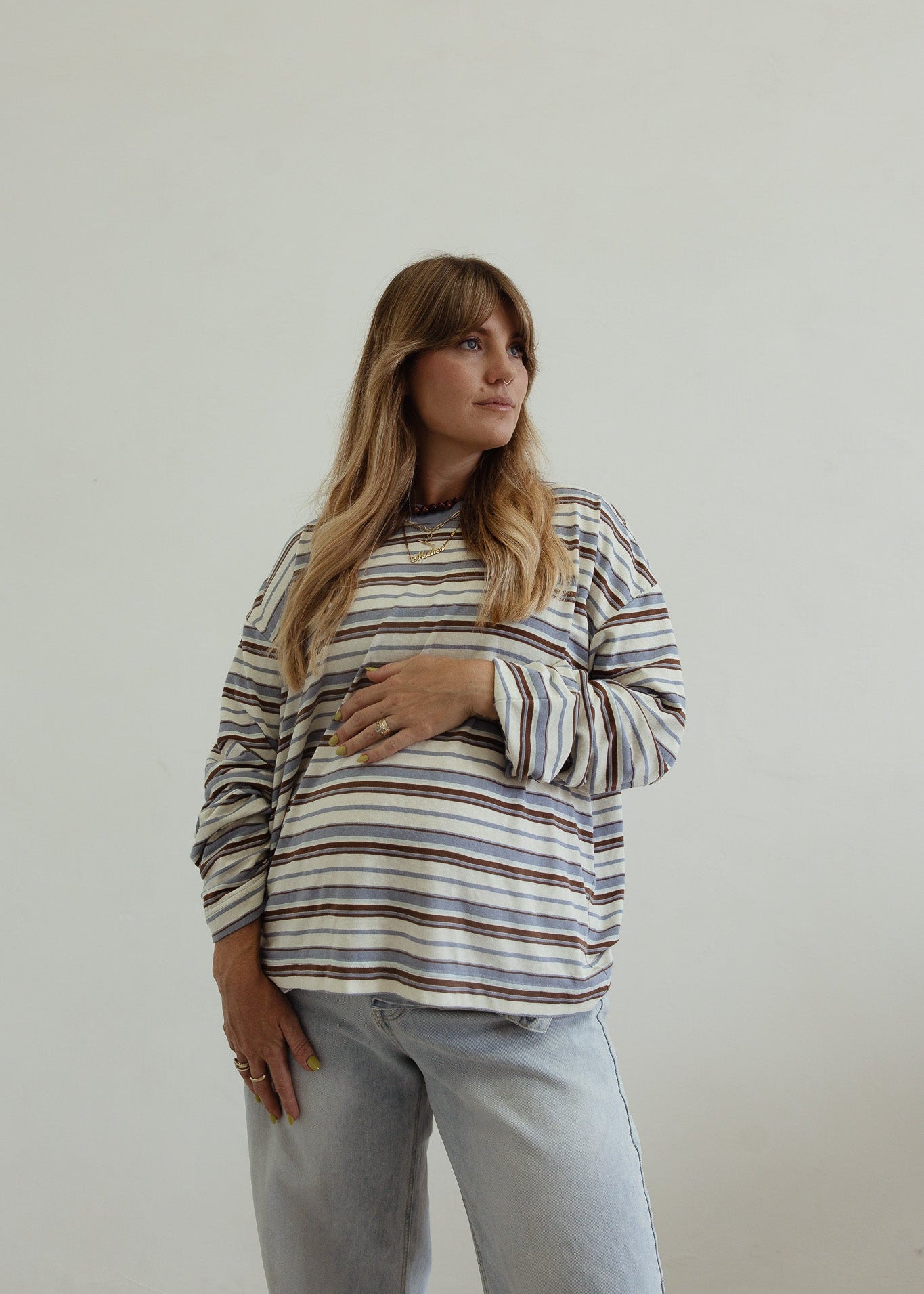 Woman wearing a striped sweater and light blue jeans against a plain background