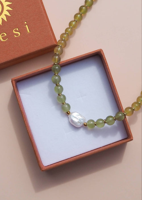 Necklace with green beads and a pearl in a box