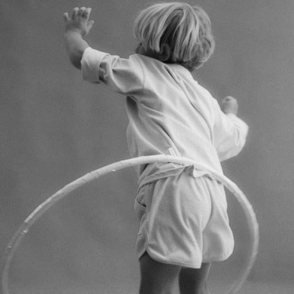 Black and white photo of a child playing with a hula hoop