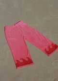 Pink pants with red wave designs on a beige surface