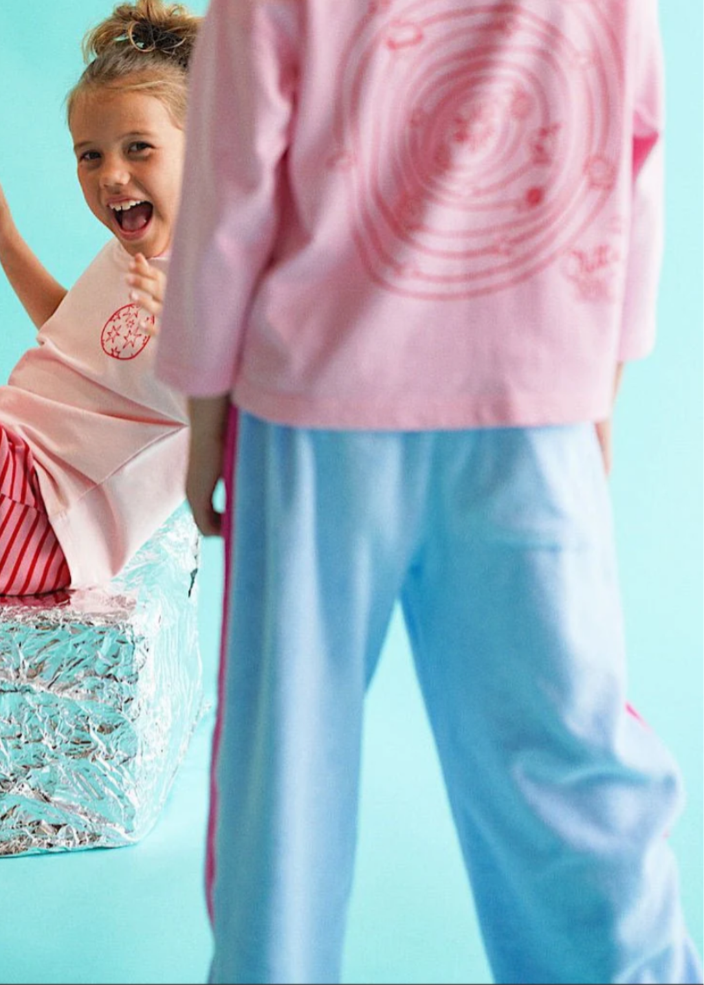 Two children playing in a pool with a light blue background