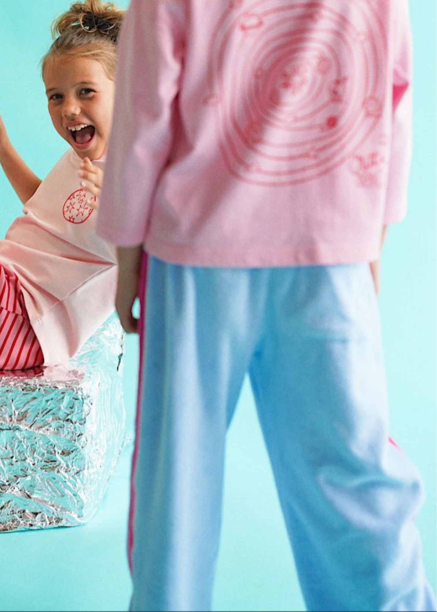 Two children playing in a pool with a light blue background
