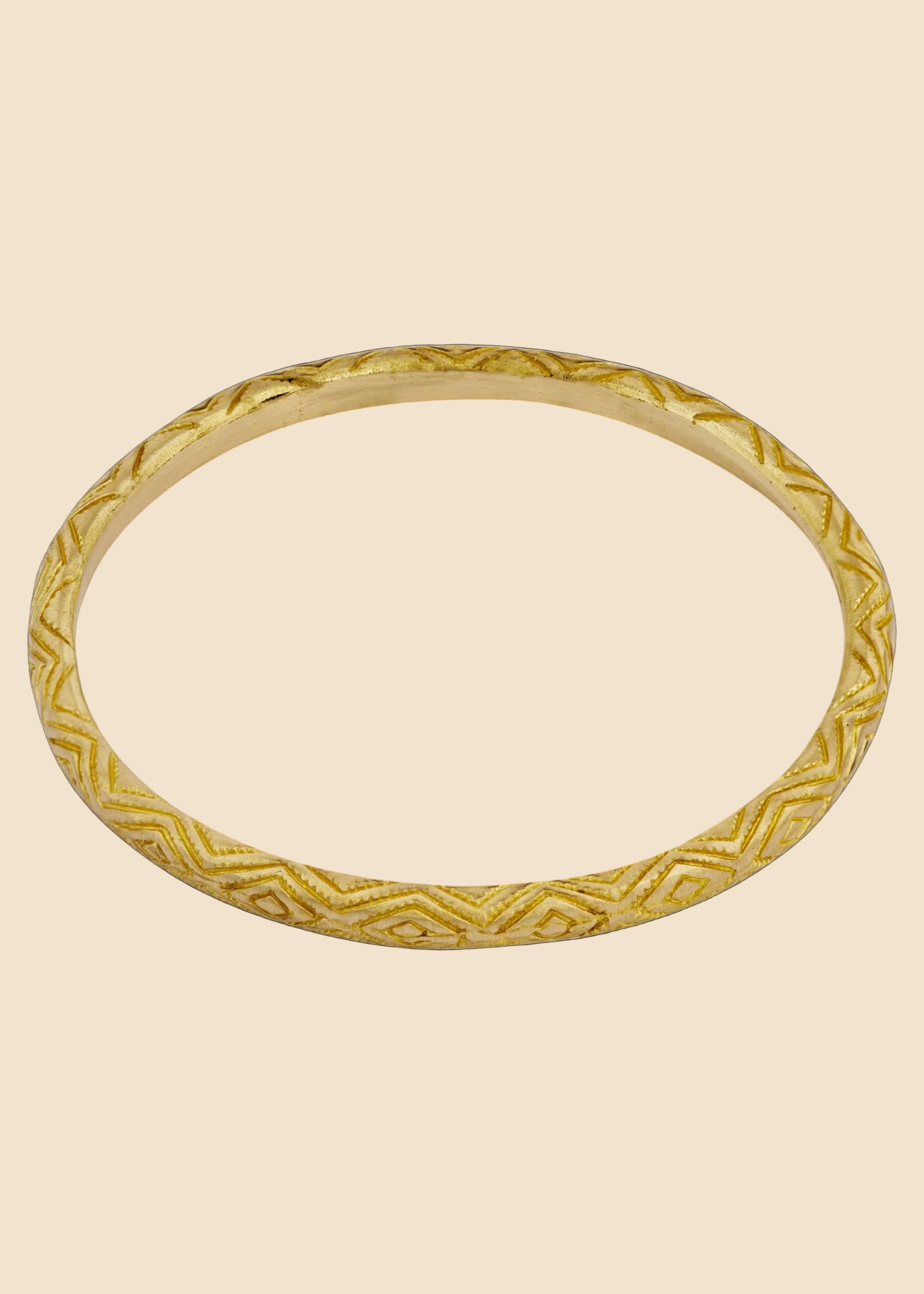 Gold bracelet with intricate design on a white background