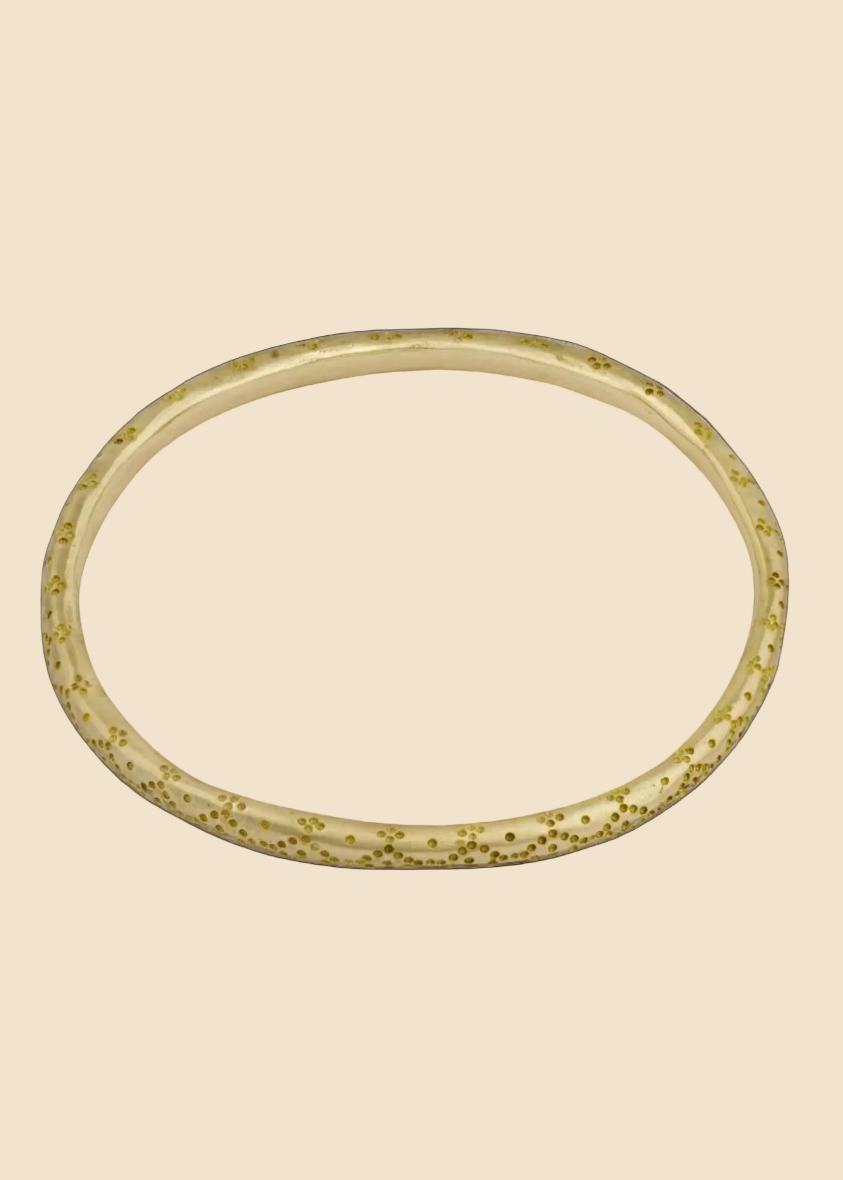 Gold bracelet with a textured pattern on a white background