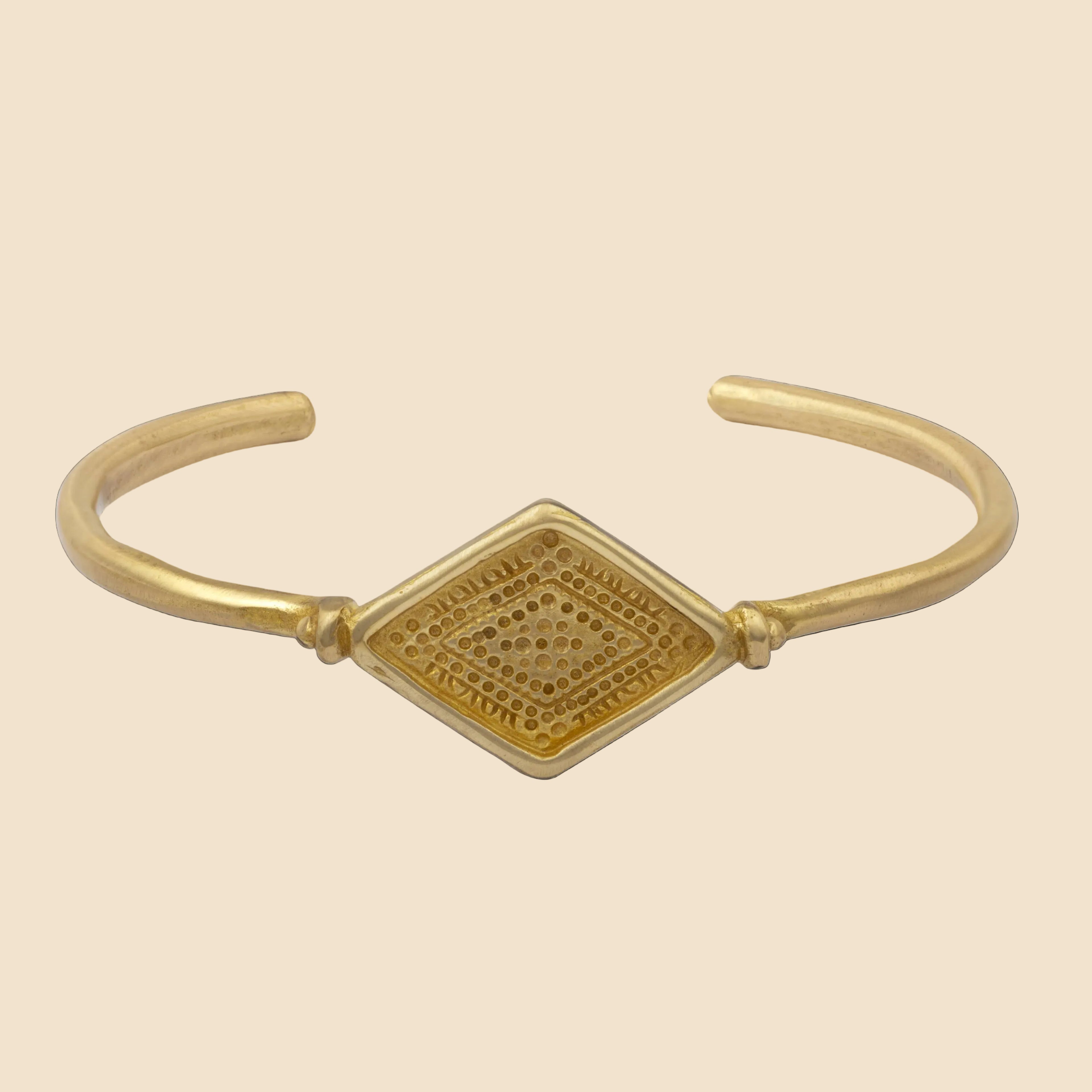 Gold bracelet with a geometric design on a white background