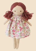 Toy doll with red hair and floral dress on a white background