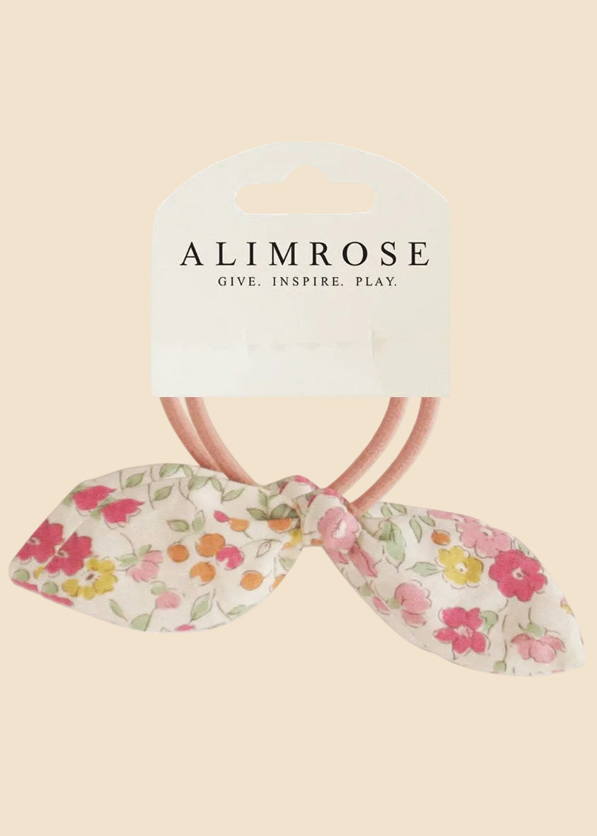 Floral hair bow with pink elastic band on Alimrose packaging