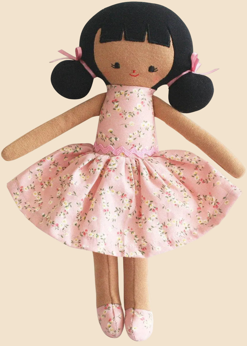 Toy doll with a pink floral dress on a white background