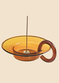 Amber-colored glass bowl with a handle on a white background
