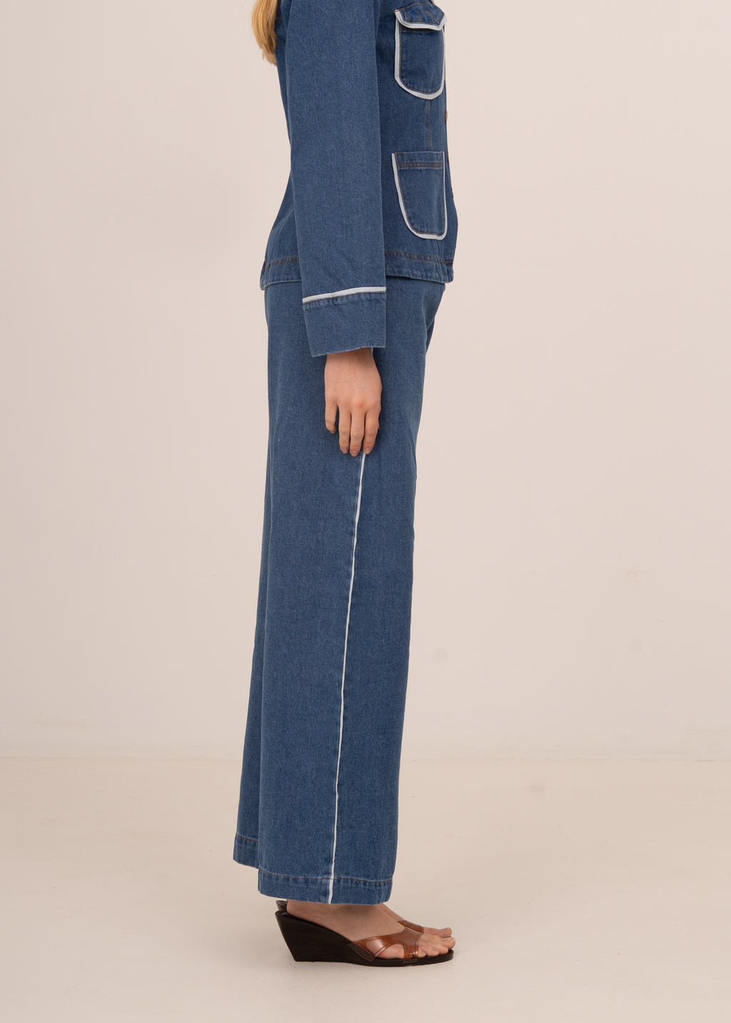 Person wearing a blue denim outfit on a beige background
