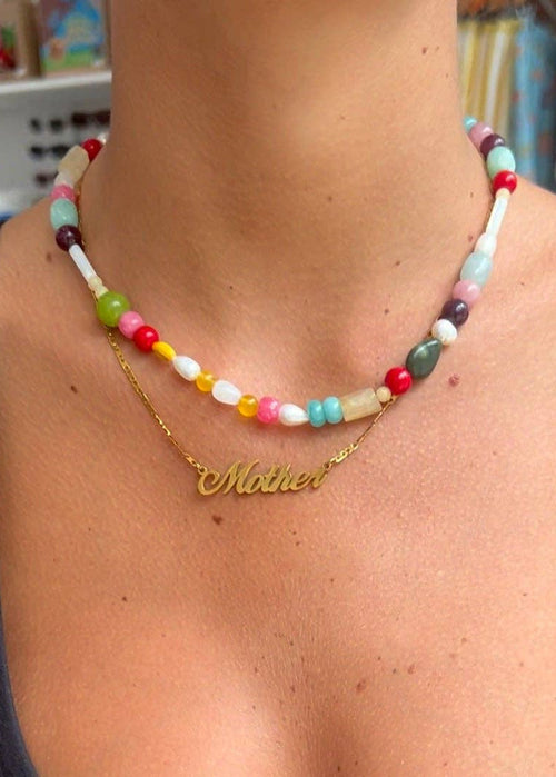 Colorful beaded necklace with a gold 'Mother' necklace on a person's neck.