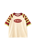 A short-sleeve raglan t-shirt with a cream-colored body, burgundy and lime green striped sleeves, and a central oval graphic that reads 'BY BILLIE' in white text.