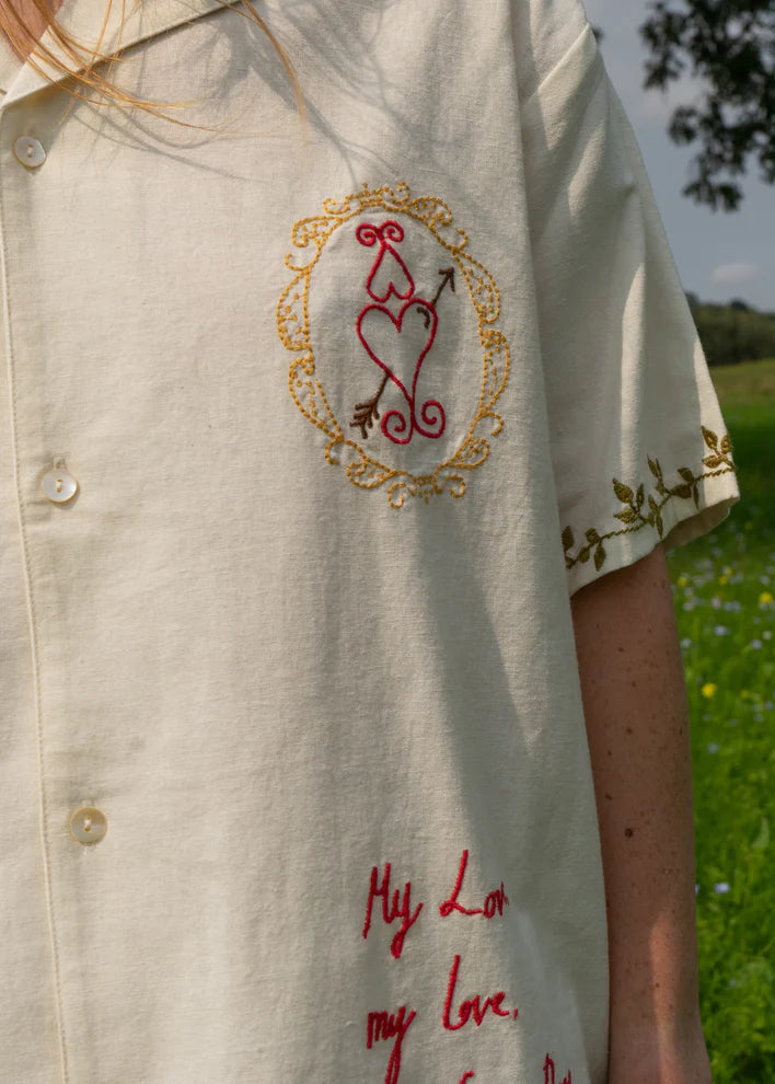 Beige shirt with embroidered design and text in a field