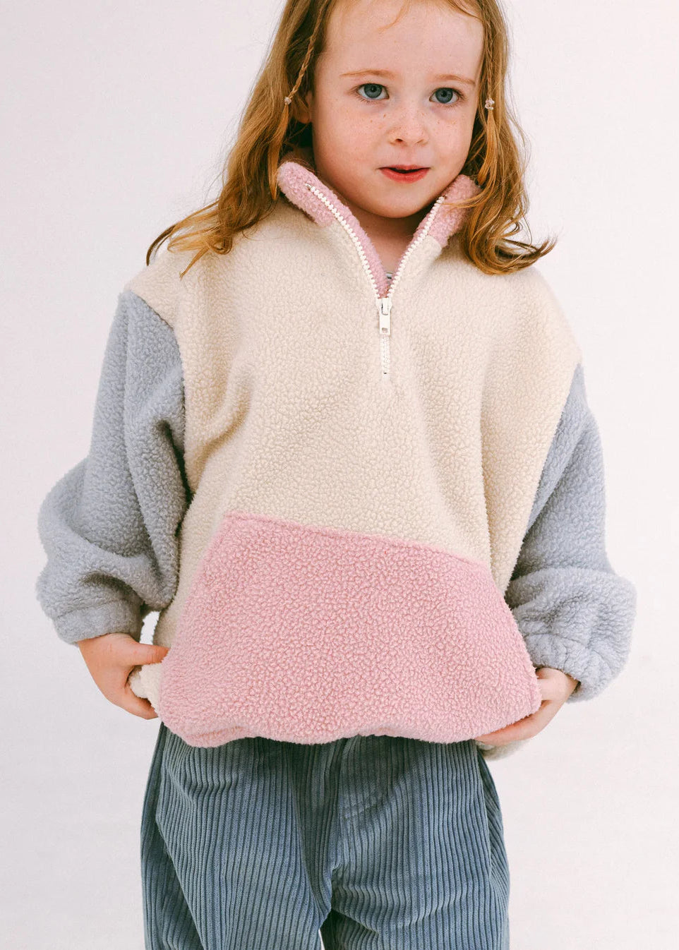 Child wearing a colorful fleece pullover with a plain background