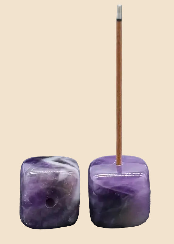 Two polished purple amethyst cube incense holders on a solid beige background, with one holder containing a single incense stick.