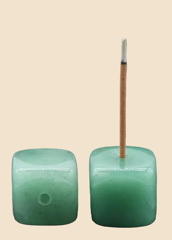 Two square green jadeite crystal incense holders on a solid beige background, with one holder containing a single incense stick.
