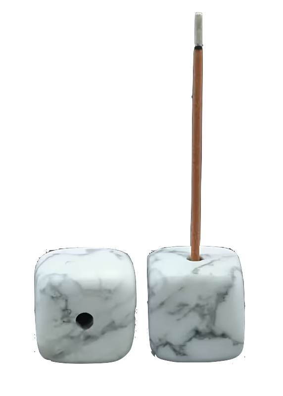 Two white marble cube beads with gray veining, one showing a side hole and the other standing upright with a thin brown incense stick inserted, on a plain white background.