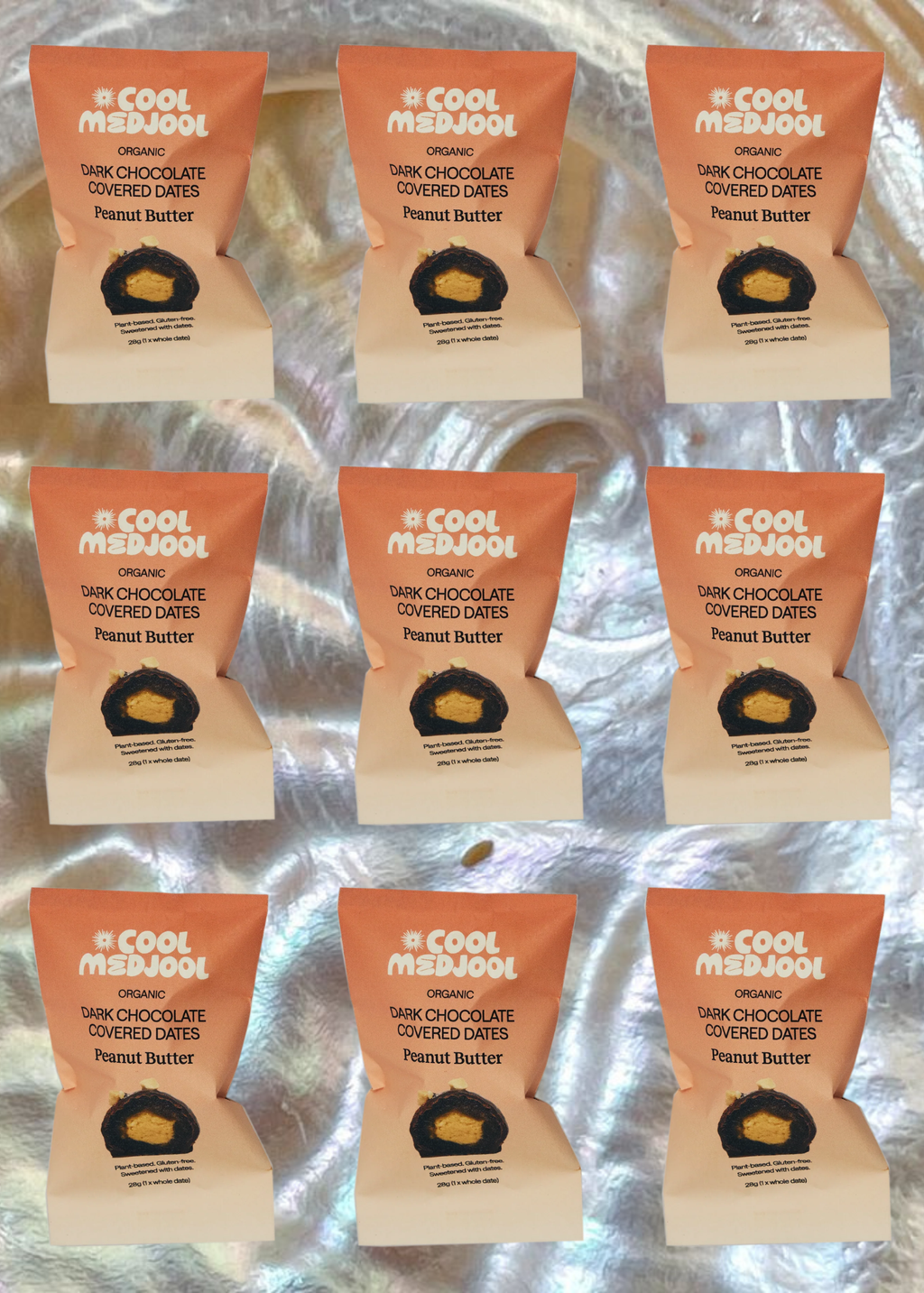 Multiple packages of 'A Cool Medjool' dark chocolate covered dates with peanut butter on a reflective surface.