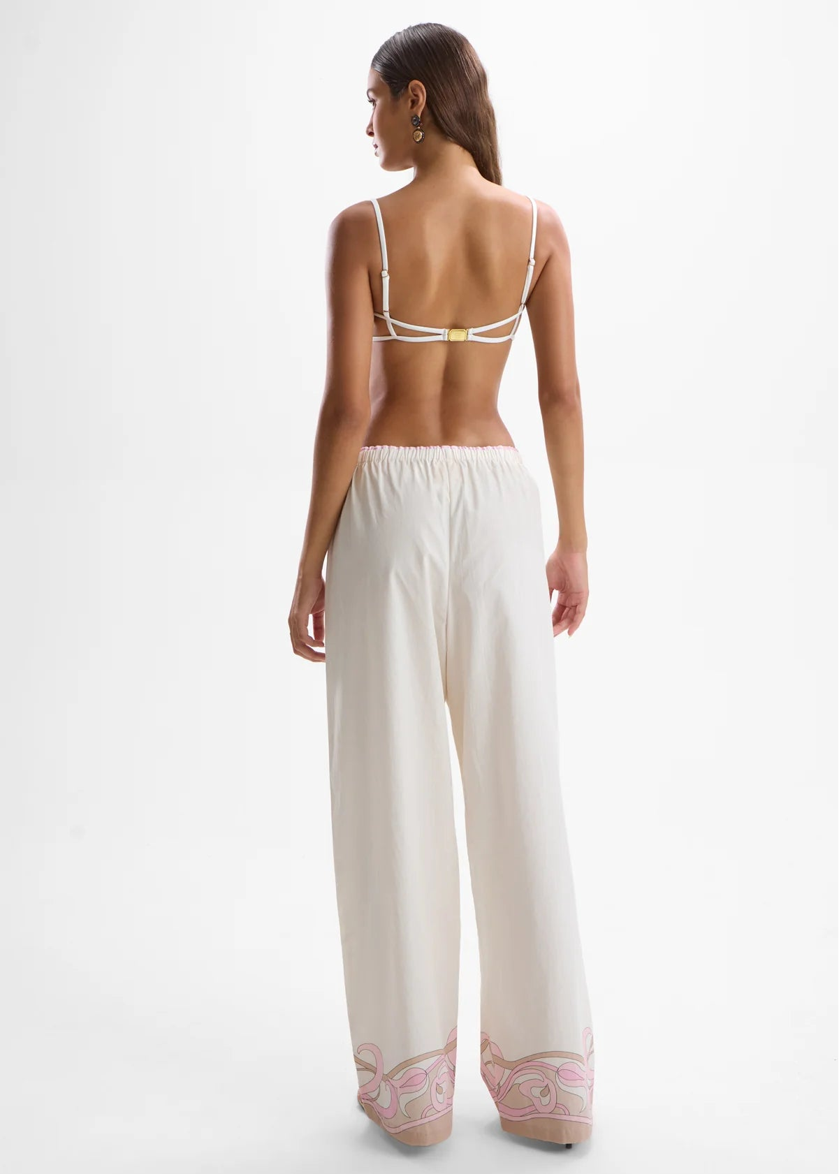 Woman wearing a white lace-trimmed top and pants on a white background