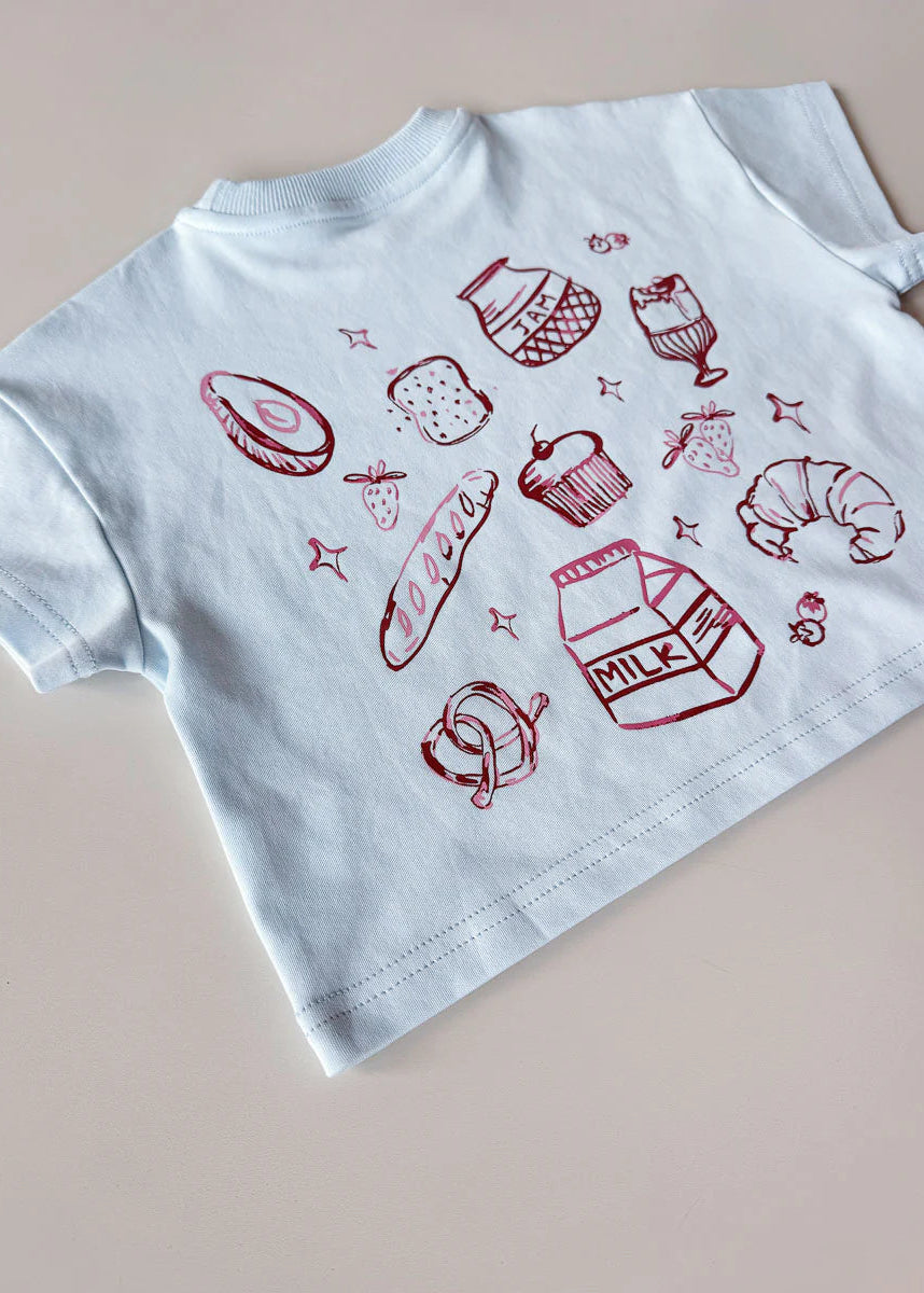 White t-shirt with red food illustrations on a beige background