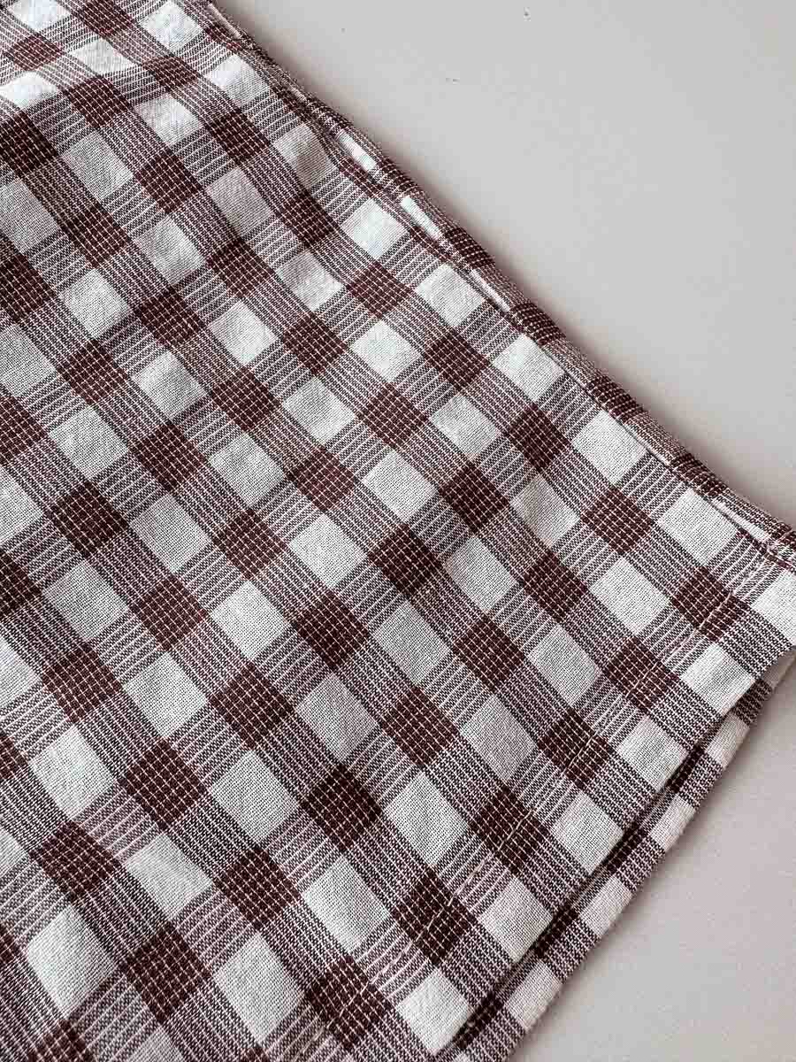 Plaid fabric with brown and white pattern on a light gray background