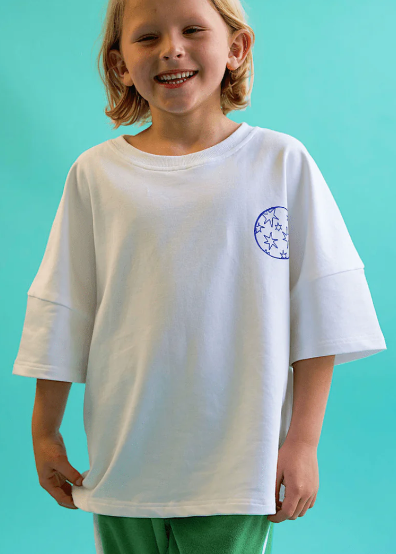 Child wearing a white t-shirt with a logo on a turquoise background