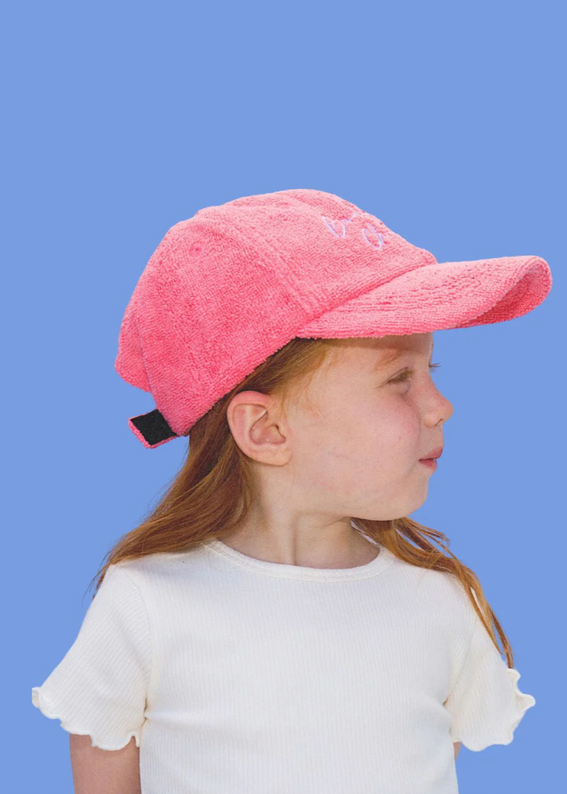 Child wearing a pink cap against a blue background