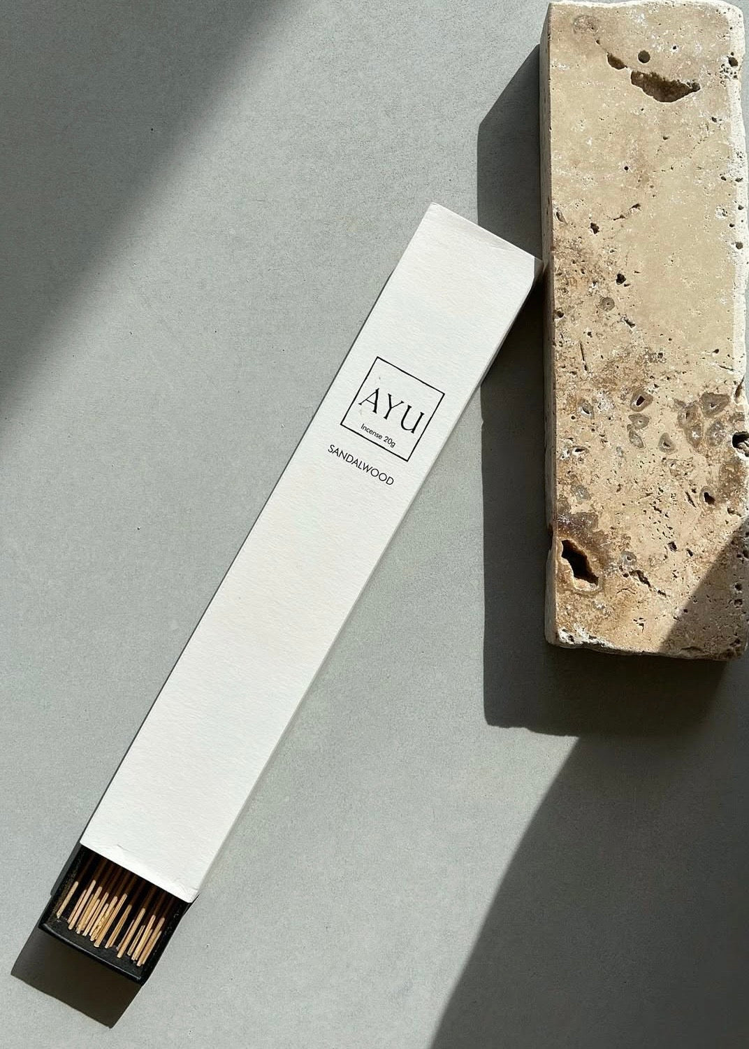 Matchstick box labeled 'AYU' next to a stone block on a gray surface