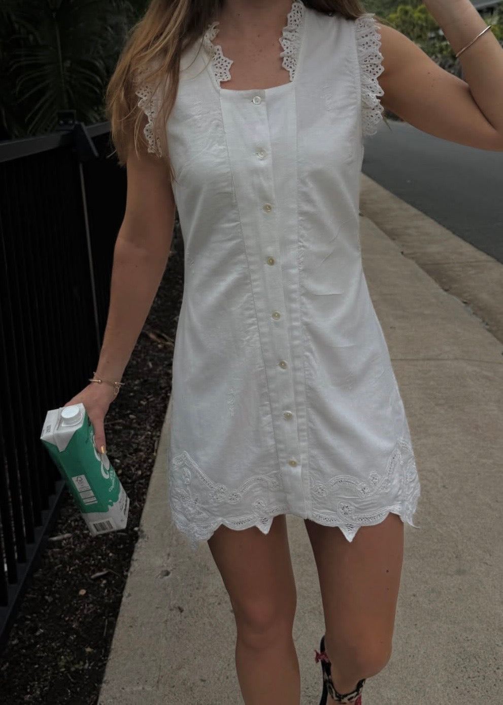 Woman wearing a white dress with lace details outdoors.