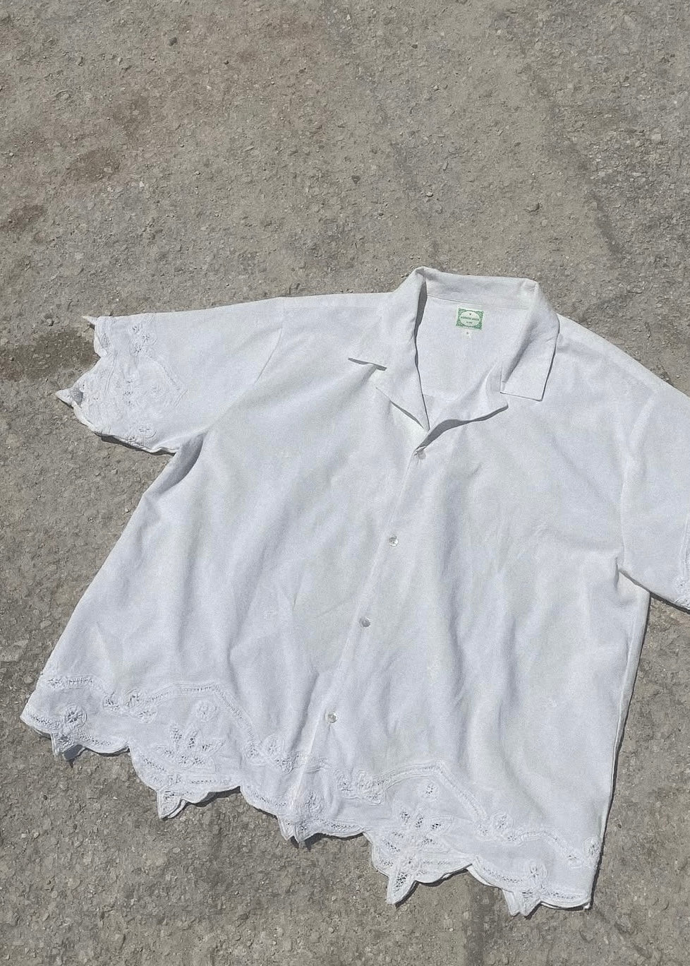 White lace-trimmed shirt on a gray concrete surface
