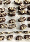 Chocolate-covered treats with a crumbly topping on a baking sheet