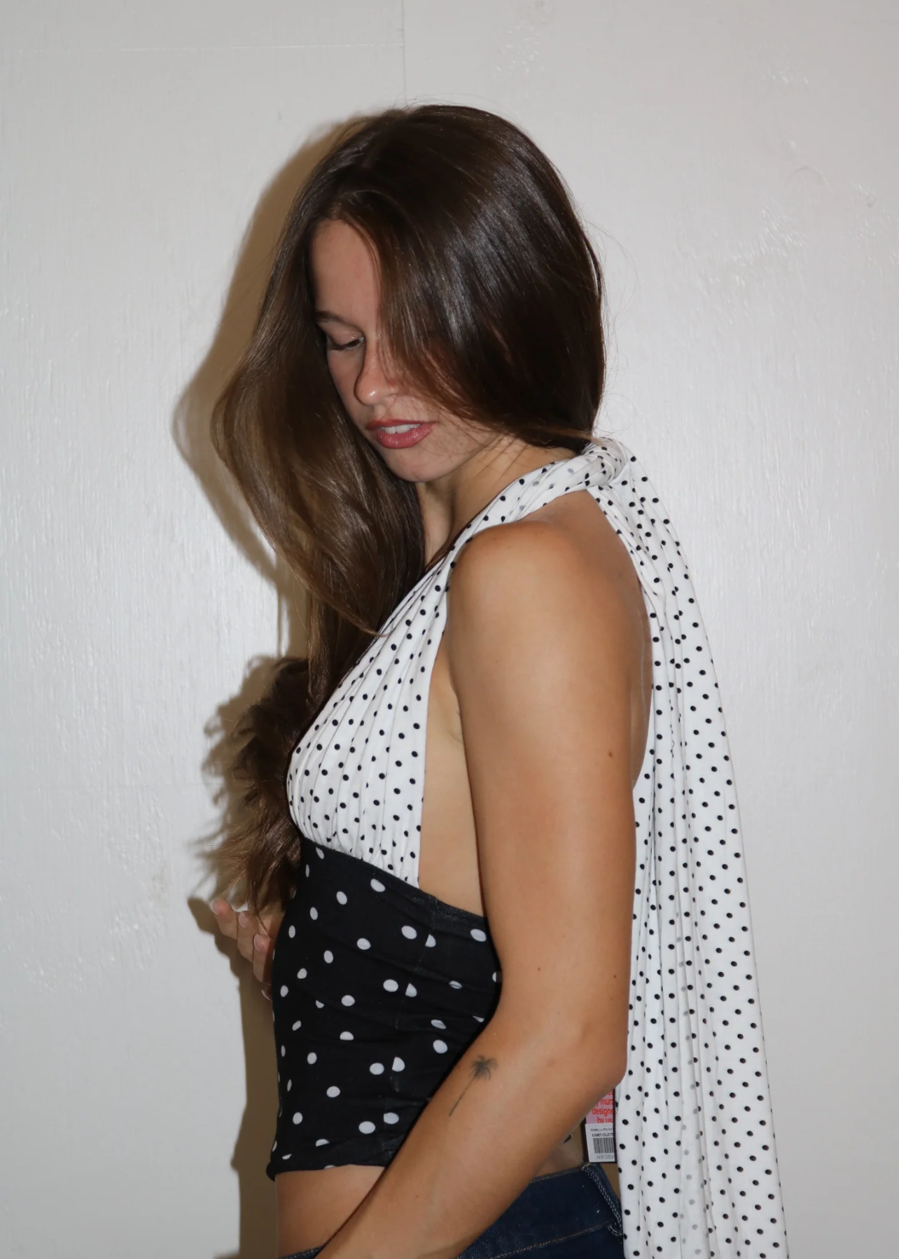 Woman wearing a black and white polka dot top with a plain background