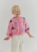 Child wearing a pink cardigan with star patterns on a plain background