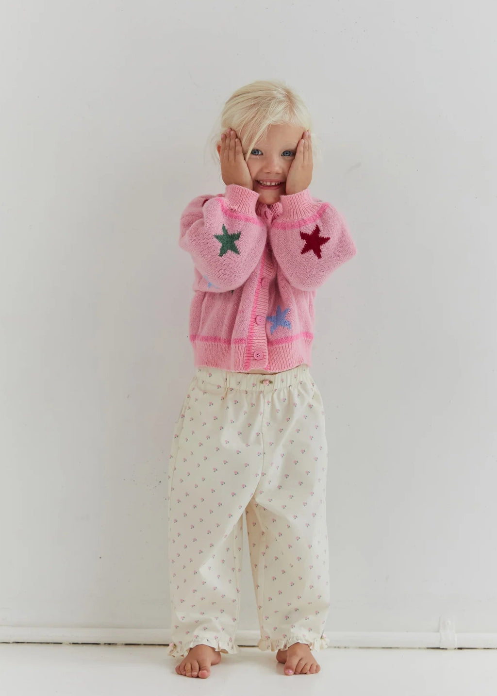 Child wearing a pink fleece jacket with star patterns on a white background