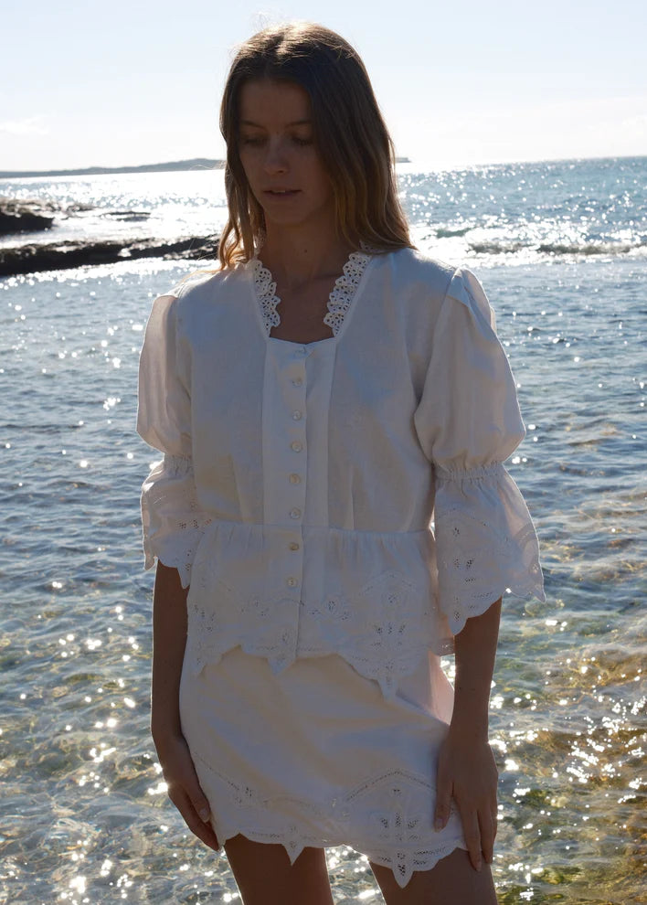Woman wearing a white dress standing by the water