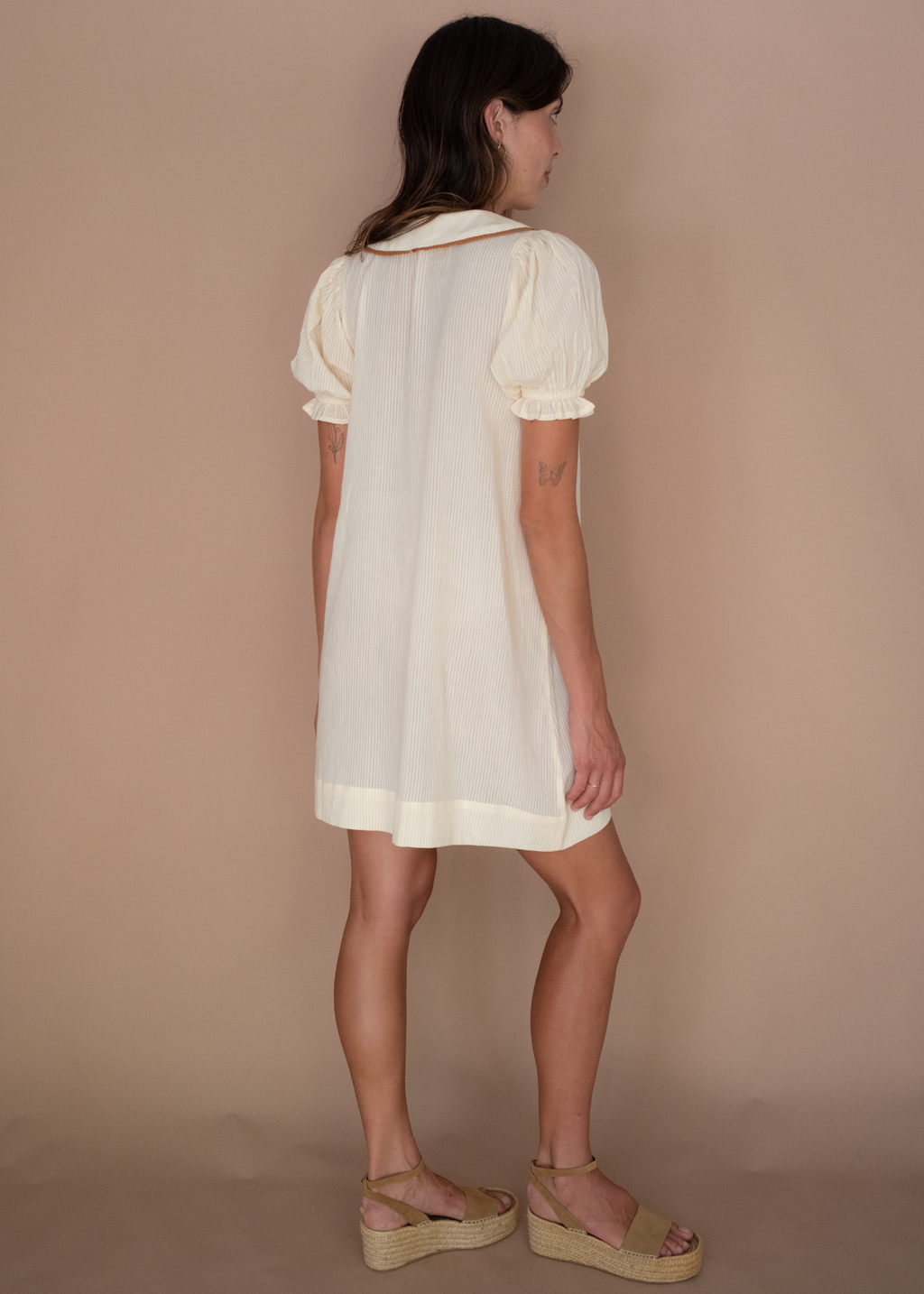 Woman wearing a white dress against a beige background