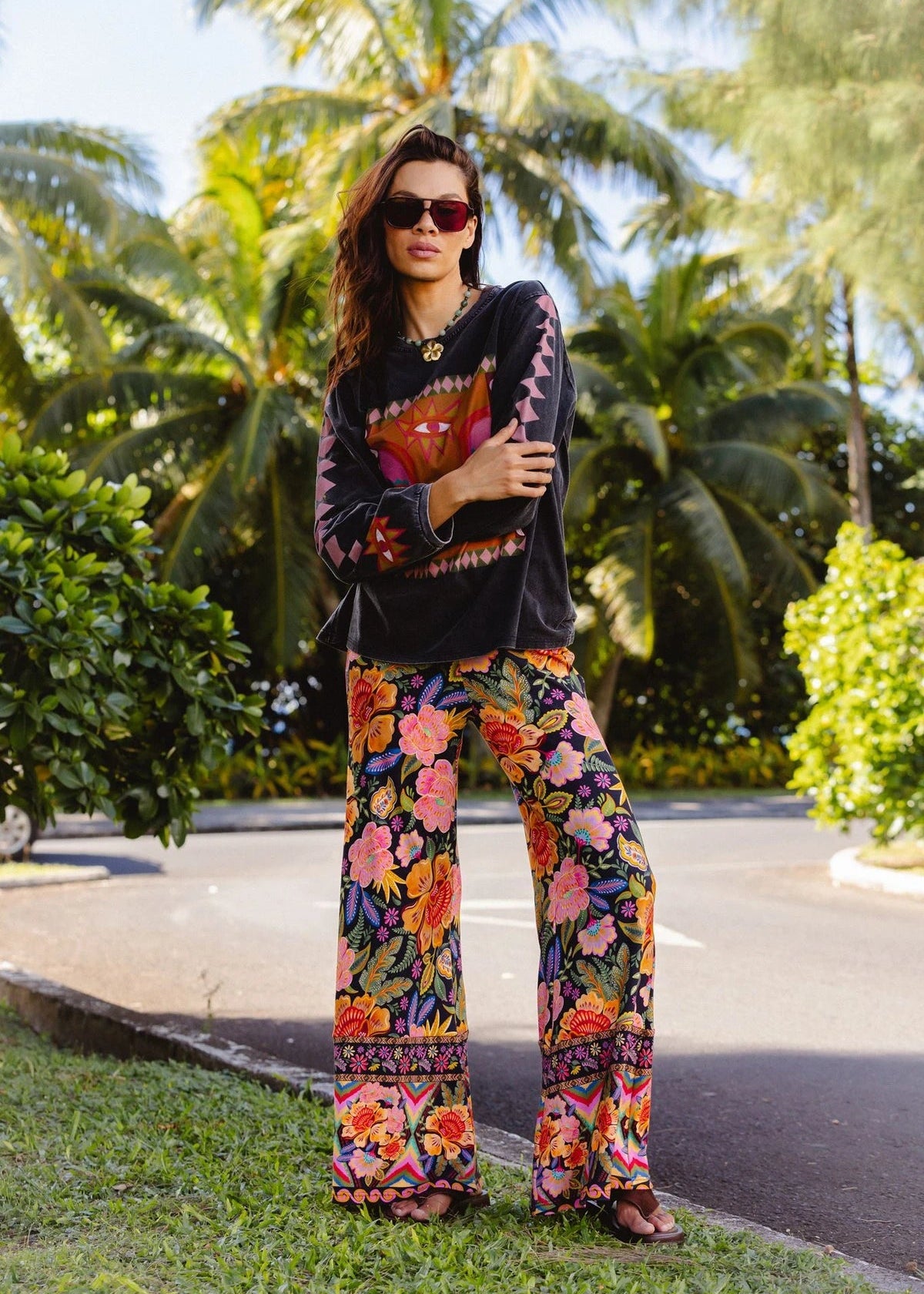 Woman in a colorful outfit standing outdoors with greenery in the background