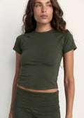 A woman wearing a fitted short-sleeve crop top in olive green, paired with matching green bottoms, photographed against a plain light background.