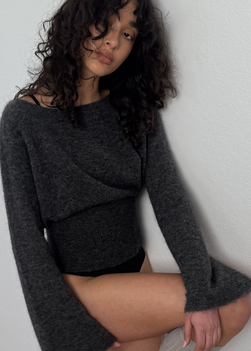 Woman wearing a dark gray long-sleeve top against a plain background