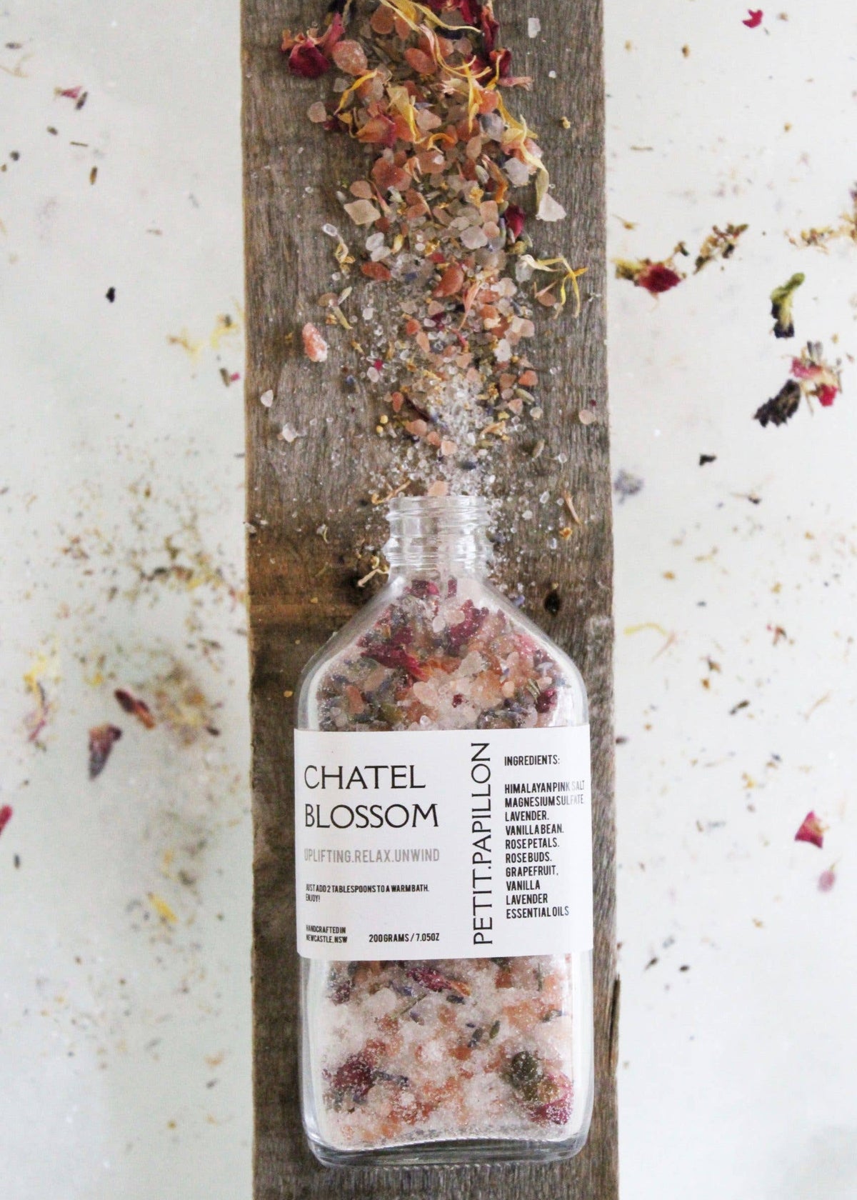 Bottle of Châtel Blossom Petit Papillon on a wooden board with flowers.
