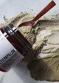 Jar of Petit Papillon clay mask with a wooden spoon on a white background