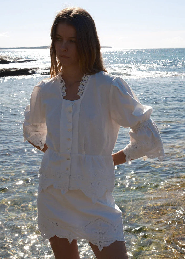 Woman wearing a white dress standing by the water