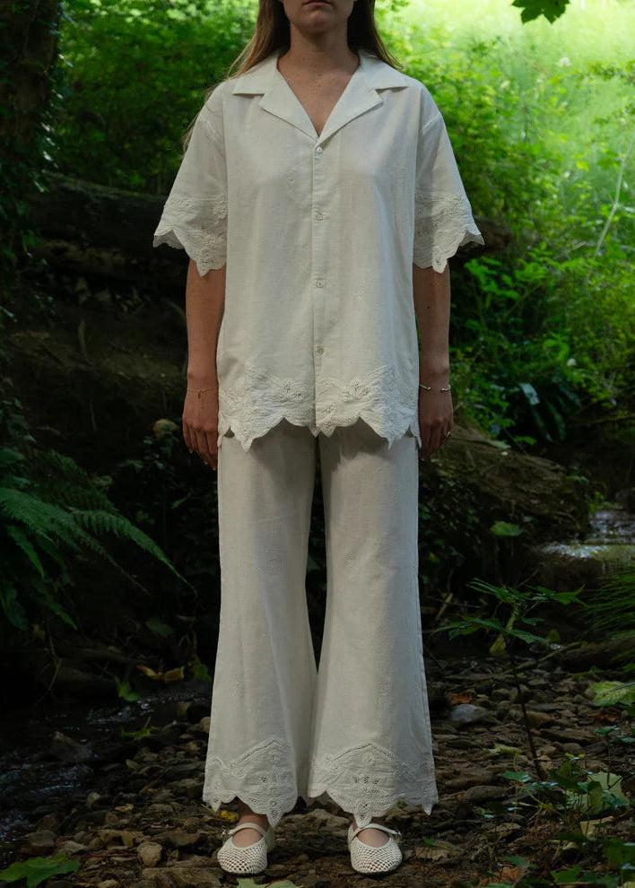 Person wearing a white outfit with lace details in a forest setting