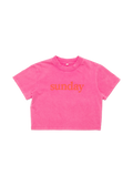 A bright pink short-sleeve crop top t-shirt with the word 'sunday' printed in orange across the chest, displayed flat against a white background.