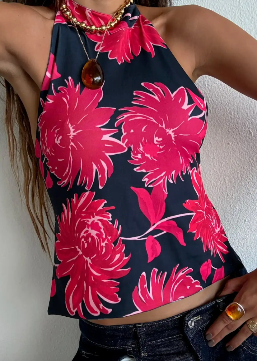 Woman wearing a black tank top with pink floral pattern against a white wall.
