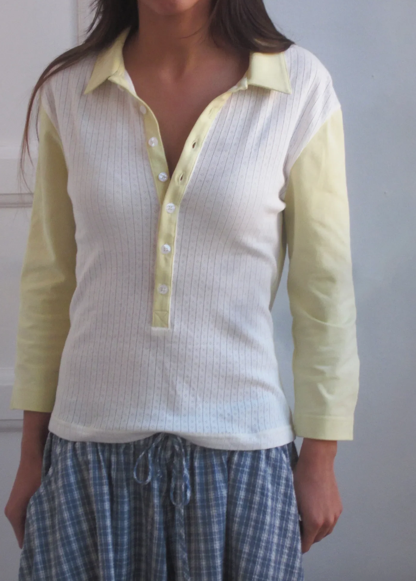 Person wearing a white and yellow long-sleeve shirt with a plain background