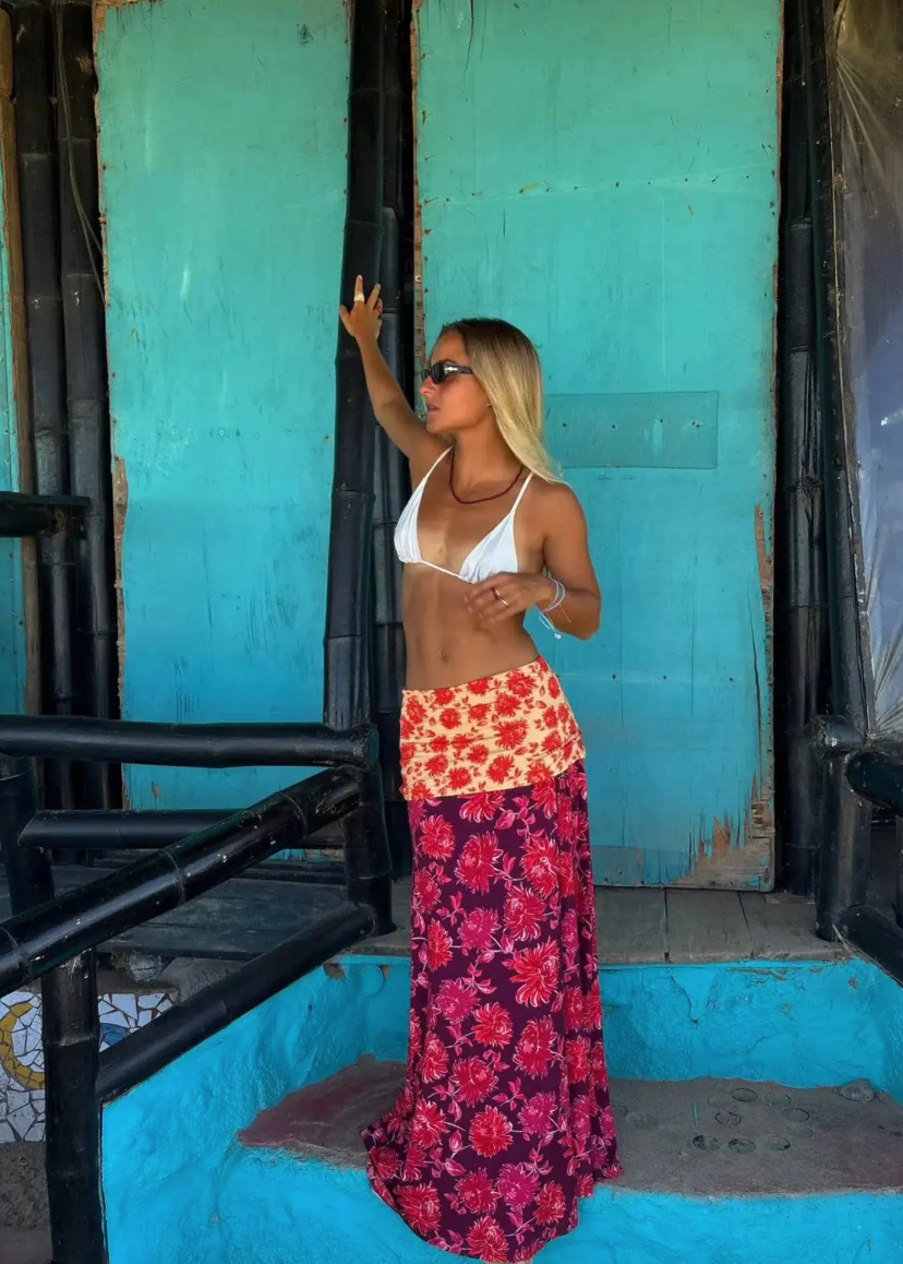 Woman in a colorful outfit standing in a turquoise room with black metal bars.