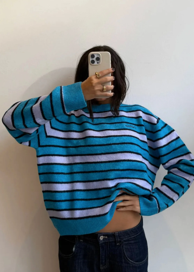 Person wearing a blue and white striped sweater against a plain background